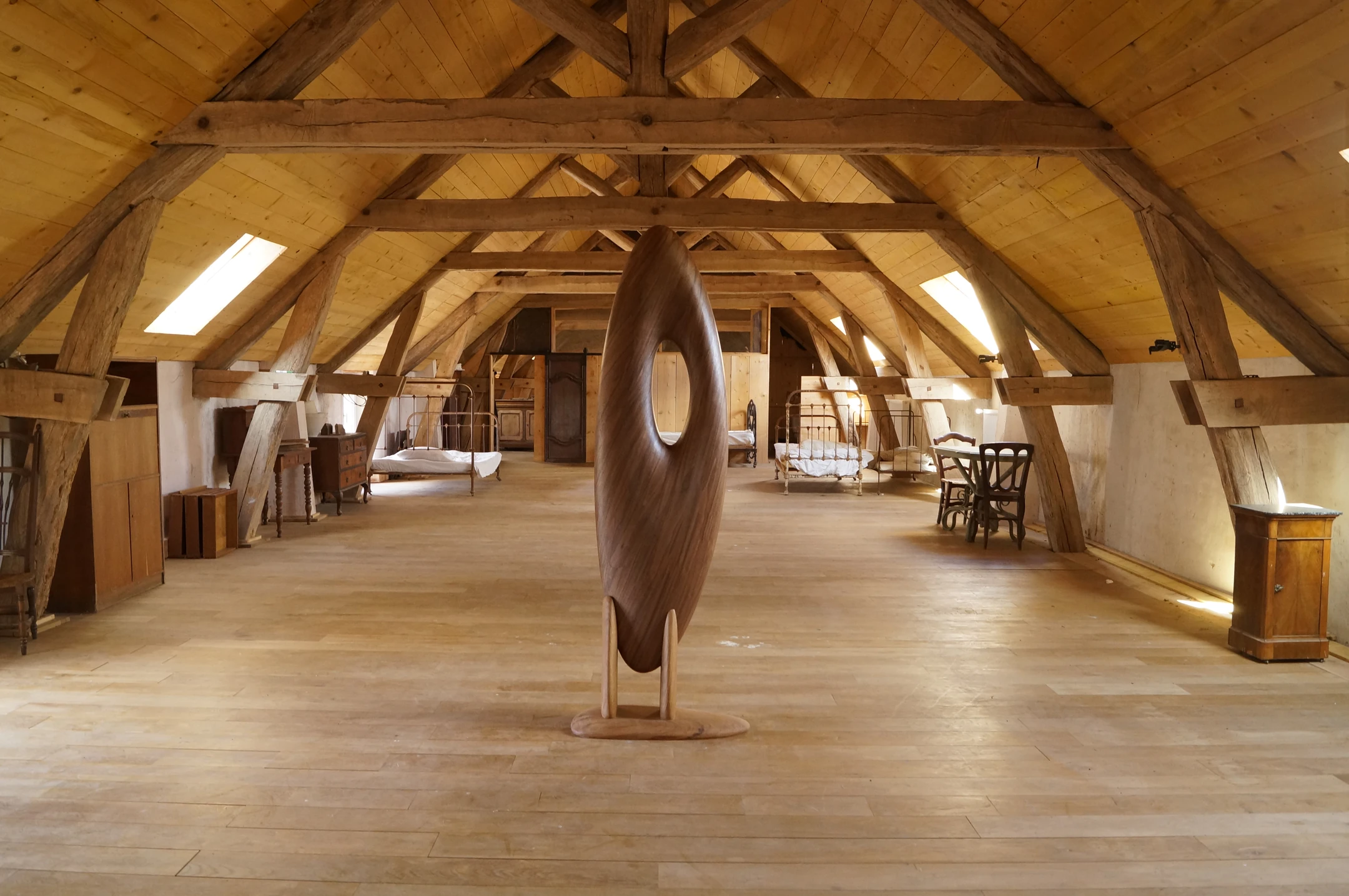 A carved wooden pebble on a stand beneath a timber roof structure.