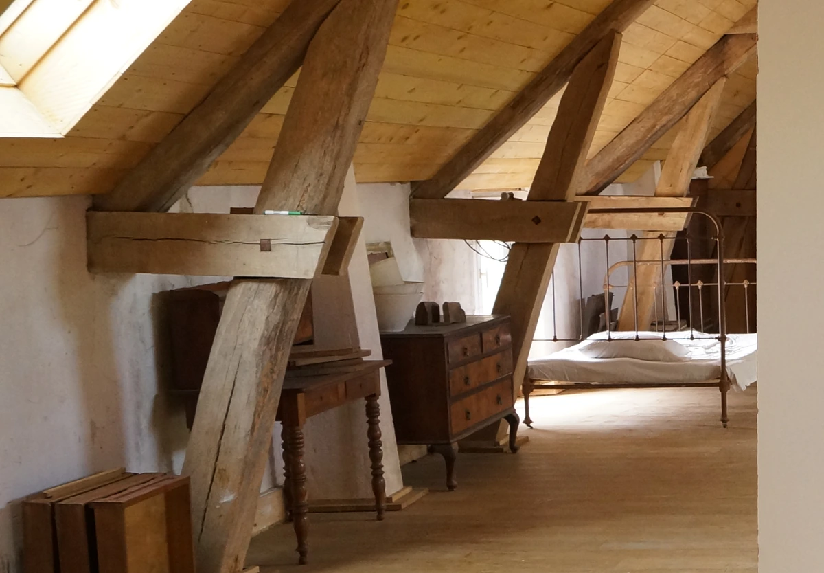 Interior view of La Cheraille: roof structure, rooflight and furniture, cropped from a photograph of the pebble.